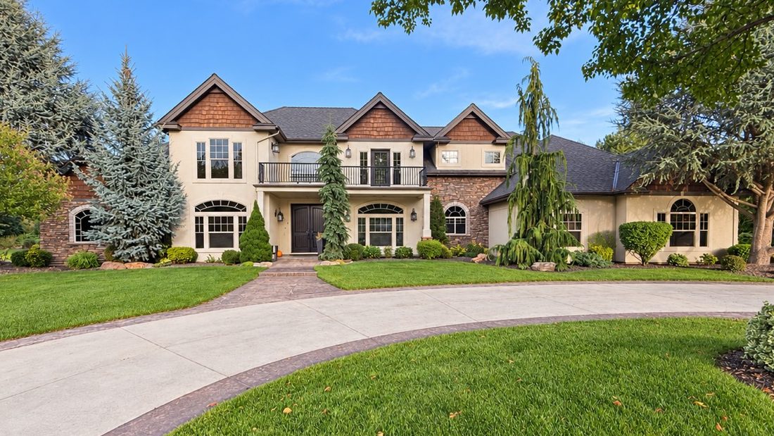 Front of a two-story home with a covered front porch, a balcony and landscaped beds